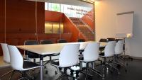 Conference room with large glass wall, staircase in background.